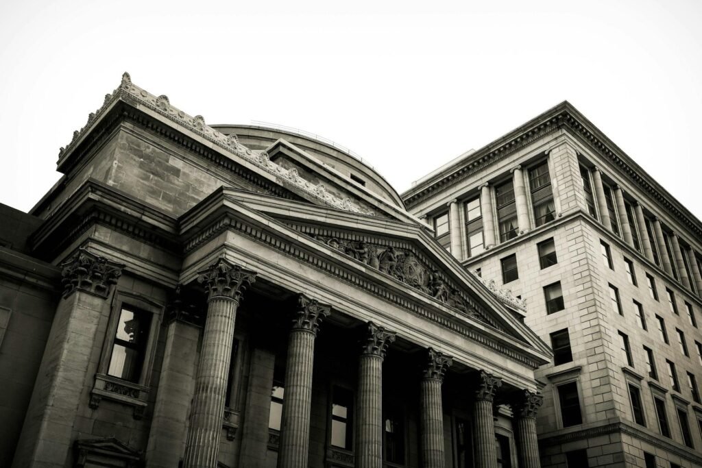 Low-angle view of a domed neoclassical bank building with Corinthian columns beside a tall stone office block