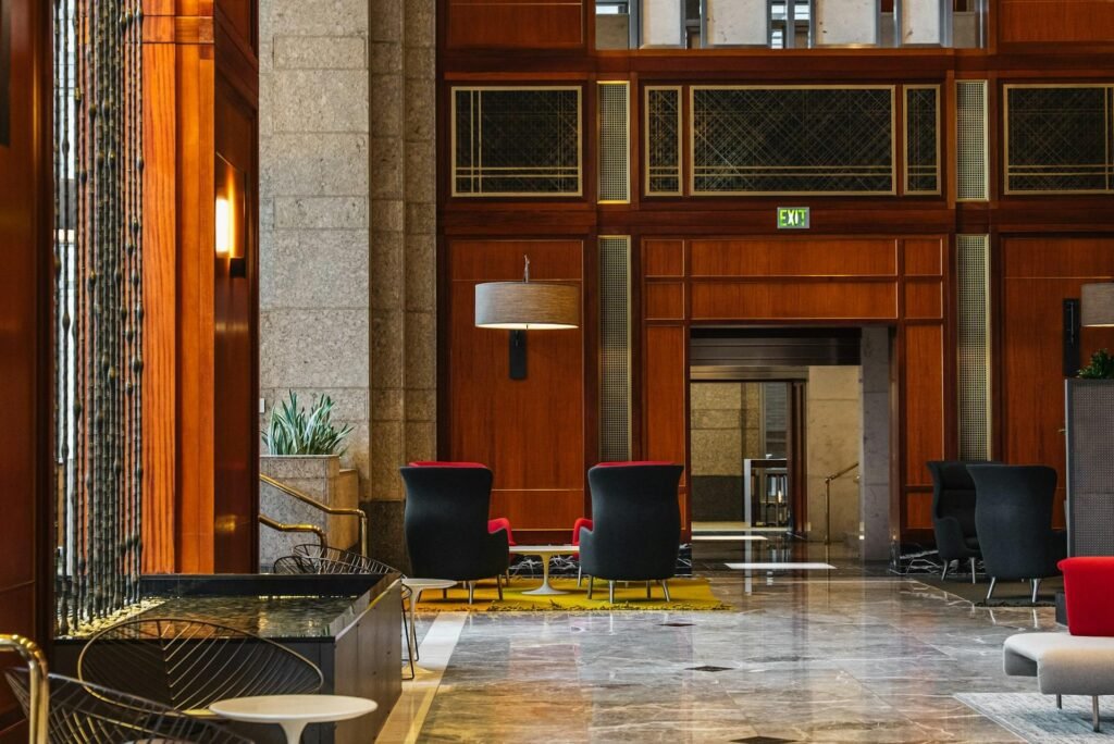 Wood-panelled office building lobby with lounge armchairs, warm lamplight and a polished marble floor