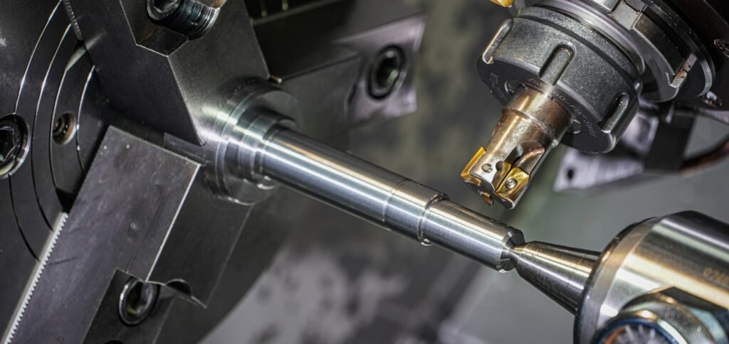 A metal rod held in a lathe chuck being cut by a machining tool